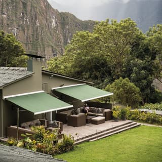 Luxury bungalow with green awnings and outdoor seating area at Machu Picchu