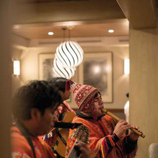 Peruvian musicians in traditional Peruvian dress playing pipes and a guitar