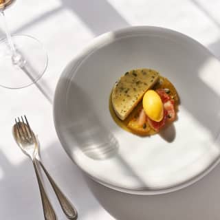 Les Agrumes et huile d'olive, served with a citrus quenelle in the shallow crater of a white dessert plate, seen from above.