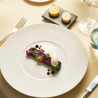 Looking down on terrine log of garden beetroot with a quenelle of horseradish sorbet, herb and flower-shaped garnishes.