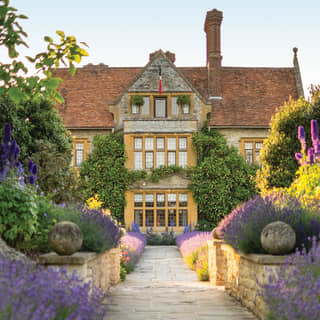 Stone path lined with lavender leading to a vast rural mansion