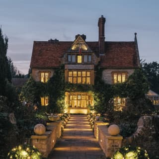 Exterior of Le Manoir glowing with festive lights in the evening