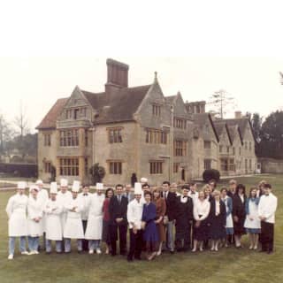 An old photograph of the Le Manoir Aux Qaut'Saisons team, with staff and chefs in toques, taken on the lawns of the property.