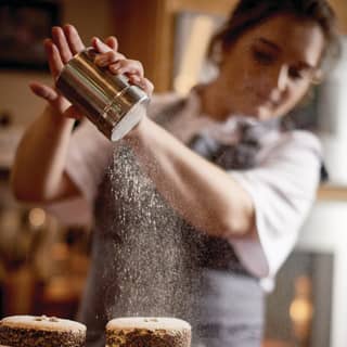 Girl pouring icing sugar from a metal icing sugar shaker