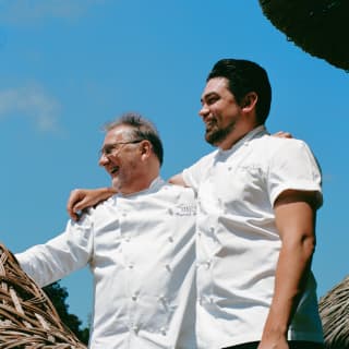 Low-angle shot of Chef Patron Raymond Blanc and Executive Chef Luke Selby smiling, with arms on each other's shoulders.