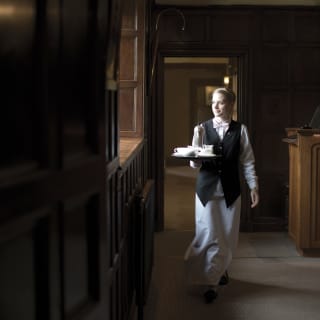 A staff holding a tray walking through a hotel's corridor