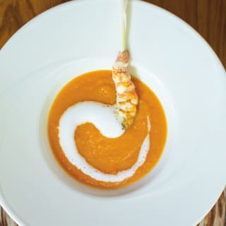 Birds-eye-view of a tomato soup with a prawn garnish in a white bowl