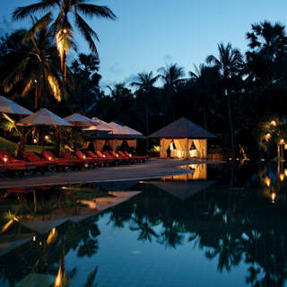 Infinity pool in evening light, surrounded by palms and sun beds