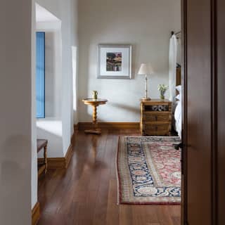 Narrow view of a light and airy hotel room with carved wooden furniture