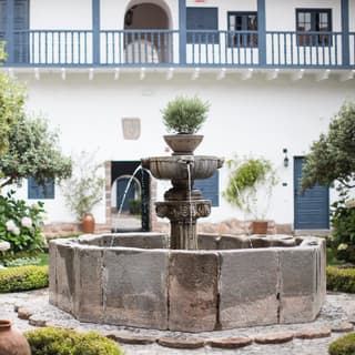Close-up of a fountain in a courtyard surrounded by a stone path and flower beds