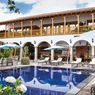 Hotel pool surrounded by sunbeds and parasols in an elegant courtyard