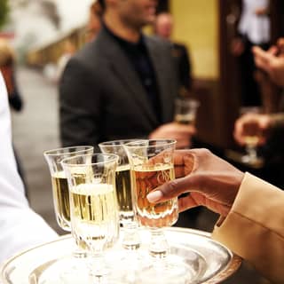 Close-up of a hand taking a glass of champagne from a silver tray