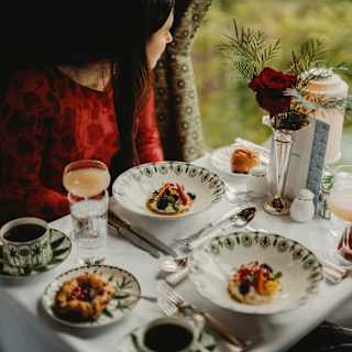Two guests gaze through the window at an Afternoon Tea in the Cygnus Car with fruit tartlets, pastries, cocktails and coffee.