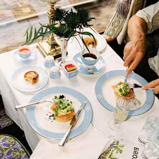 Looking down on a dining table as a guest tucks into one of two plates of salmon, while his companion's seat is empty.