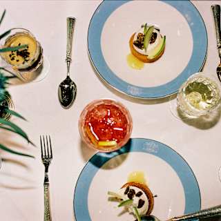 Looking down on two plates of glazed lemon tart with cream, served with glasses of white wine, Espresso Martini and Negroni.