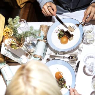 Aerial view of guests indulging in a festive starter of Chicken Liver Parfait at a table with fir spruces and crackers.