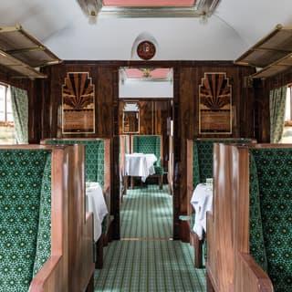 Wood panelled seats, upholstered in green geometric patterned fabrics gives a sense of luxury to this carriage interior