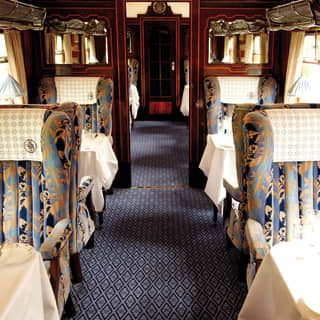 Vintage train carriage with blue liberty print armchair seating and formal dining tables