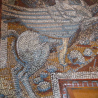 A mosaic in tiny tiles of blue and white depicts Greek God Perseus riding the winged horse, Pegasus, across golden skies