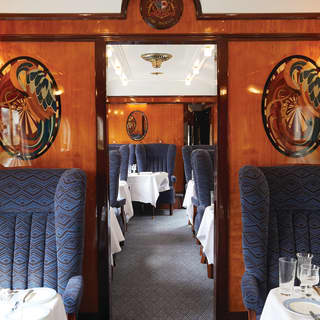 View through the aisle of a vintage train carriage with navy blue armchair seating