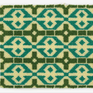 The carpet features a cream background with a cream figure of 8 within a turquoise diamond and dark green square frames