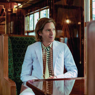 Filmmaker Wes Anderson sits at a French polished table in an art deco carriage and observes the world through the window