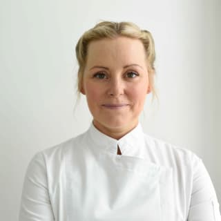 Award-winning celebrity chef, Anna Haugh, dressed in traditional high collar chef whites smiles at the camera