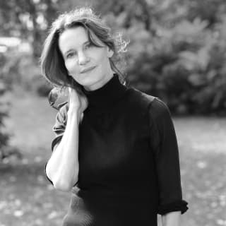 A black and white image of acclaimed author and lexicographer, Susie Dent, smiling gently as she looks directly at the camera