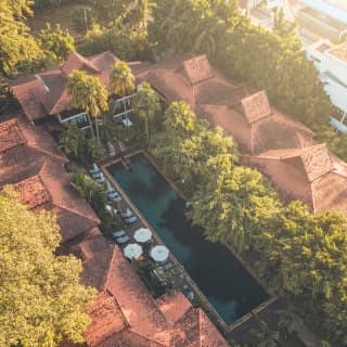 Birds-eye-view of an outdoor pool surrounded by a red-tile roofed residence
