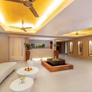 Warmly lit relaxation room with large curved sofa and water fountain