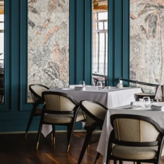William Restaurant interior detail with two dining tables and wall panels of subdued botanical prints with teal wood frames.
