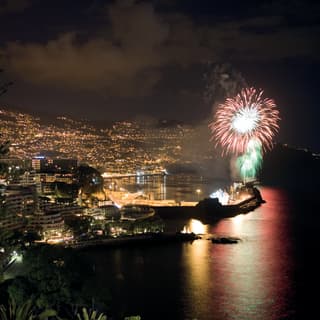 View at night from the hotel to glittering Funchal, where sprays of red and green New Year's Eve fireworks dazzle in the sky.
