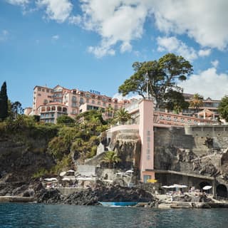 Pink facade of a Victorian hotel spread across a cliffside overlooking the sea