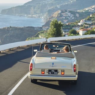 Couple in a vintage car driving along a Madeira highway