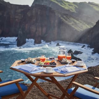 Close-up of breakfast on an outdoor table overlooking the coast