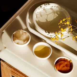 Four bowls of oils, aloe vera balsam and water, with a gypsophila sprig, seen close-up, ready for a regional spa treatment.