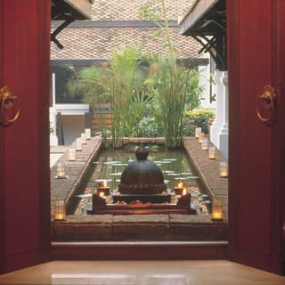 Oriental courtyard lily pond with bamboo plants and flickering candles