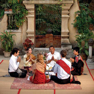 Guests sitting beside a temple joining in a traditional Baci ceremony