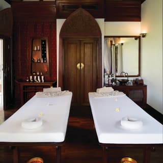Two spa treatment beds side-by-side with cabinets lined with spa products