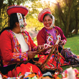 Due donne sorridenti vestiti con abiti tradizionali peruviani