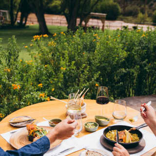 A couple enjoys lunch of suckling pig and confit duck al fresco at El Huerto, served with red wine, bread and Urubamba views.