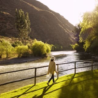 A woman wearing a poncho, walking in the Hotel Rio Sagrado gardens