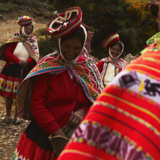 Angled image of three local women wearing tilted Montera hats and brightly woven Manta shawls over Jobona jackets for warmth.
