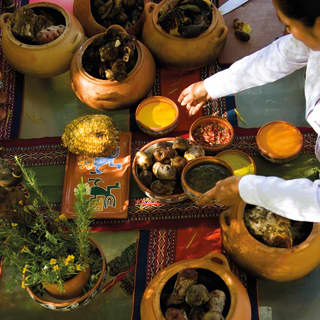 A woman selects from pots of potatoes, pulses and other ingredients at a table of variety for a Pachamanca food experience.