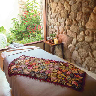 Spa treatment bed with a vibrant floral blanket on top, overlooking gardens