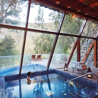Lady swimming in a plunge pool with floor to ceiling windows overlooking the treetops of Sacred Valley