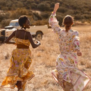 Deux femmes courent en riant dans une prairie du Botswana