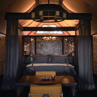 Safari lodge tent with a grand four-poster bed in mustard and dark grey accents