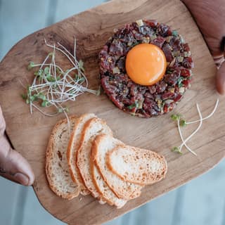 Birds-eye-view of a starter dish of melba toast with and terrine on a wooden platter