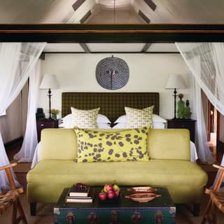 Luxurious safari lodge room with four-poster bed and lime green sofa